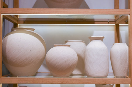 Beige vases of different sizes are on the shelf in the storeの写真素材