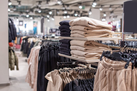 A set of beige clothes in the store on the shelf. Pants are hanging on a hangerの写真素材