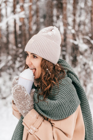 Cute girl licks snow from a mug in the woodsの写真素材