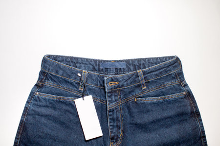 A mock-up of a white price tag card in a denim pocket is a fashionable background, a place to copy. The upper part of the trousersの写真素材