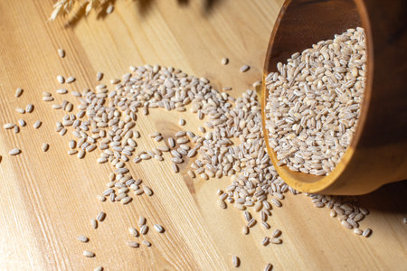 Grain cereals scattered from a wooden plate lie on the tableの写真素材