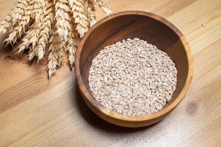 Cereal crops lie in a wooden plate on a table with wheat earsの写真素材