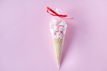 Colorful bright sweet meringues in waffle cookies lie on a pink backgroundの写真素材
