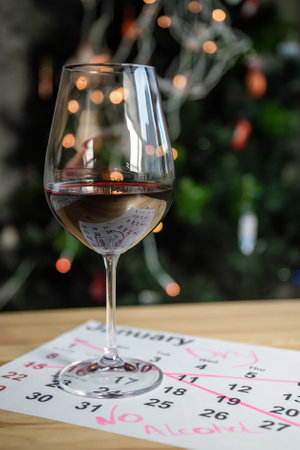A glass of wine is on the calendar near the Christmas tree with a garlandの写真素材