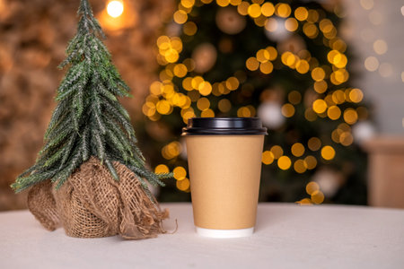 A disposable coffee cup with a lid stands near the Christmas tree. Place for advertisingの写真素材