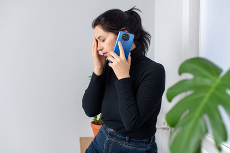 Cute girl talking on the phone with her eyes closed and gets bad newsの写真素材