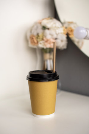 A disposable eco-friendly paper cup with a straw and a black lid is on the shelfの写真素材