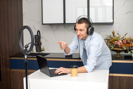A man with headphones is streaming to his phone. Work on a laptop . Pointing with your fingerの写真素材