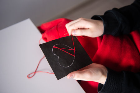 The child's hands make a card with a heart for mother's Day with red threadsの写真素材