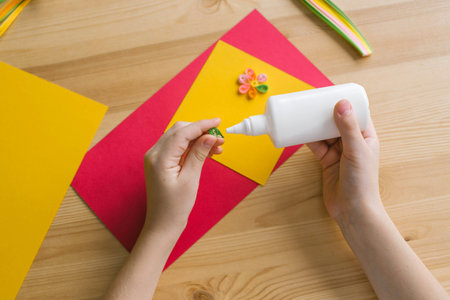 The child's hands make a card out of quilling, glue a strip of paper with white glueの写真素材