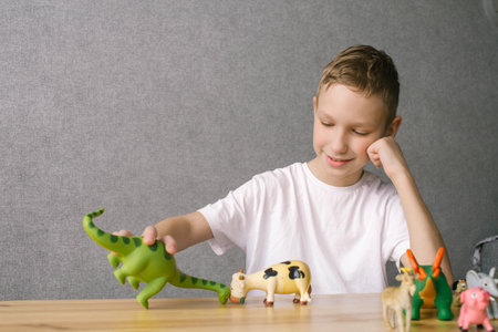 Little boy playing with toys at home. Child having fun with colorful dinosaurs.の写真素材