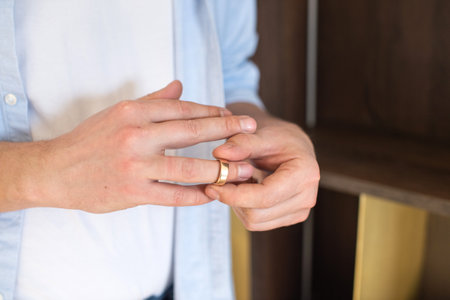 A man removes a gold wedding ring from his right handの写真素材