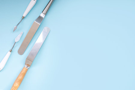 Professional set of spatulas for icing large cakes. starter kit for decorating a cake. Confectioner's tools on a blue background, pastry spatulas. Place for textの写真素材