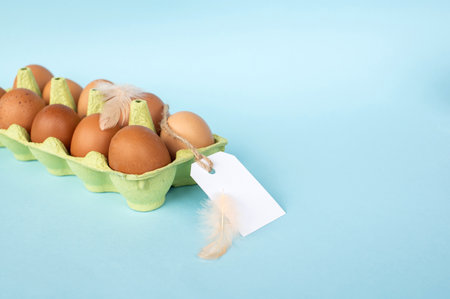 Chicken eggs in recycled paper tray with price tag label. Set of eggs with tag and bird feather