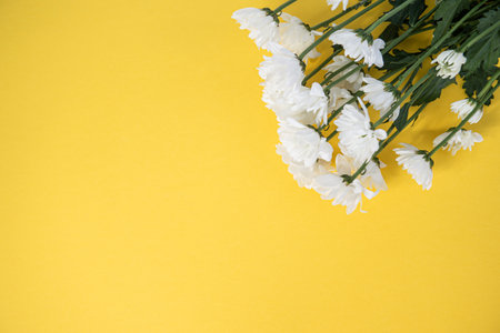 Top view of a yellow table with a mockup of blank notebooks with a bouquet of roses on the side.の写真素材
