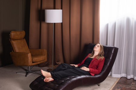 A cute girl lies with her eyes closed in a chair for psychological relief barefootの写真素材