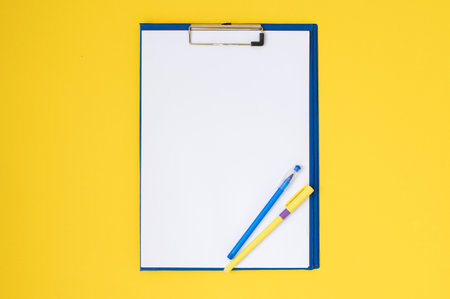 A set of blue stationery as a template with a place to copy on a yellow table, a tablet, a pen, a folder for papers and a pencil. top view, recording locationの写真素材