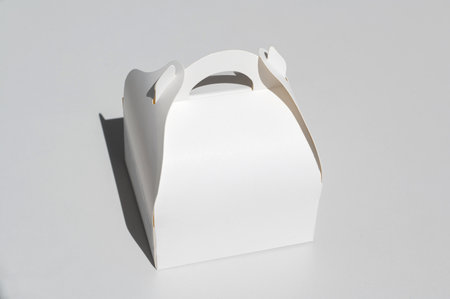 White cardboard box for a takeaway cake, highlighted on a white background with a clipping outline with a carrying handleの写真素材