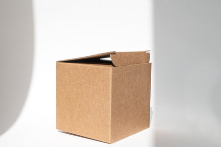 Brown open square corrugated cardboard box on a white background. An empty cardboard box with a shadow from the window. copy spaceの写真素材