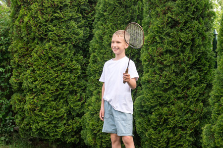 Cute left-handed boy, holding a badminton racket in his hand, active outdoor games