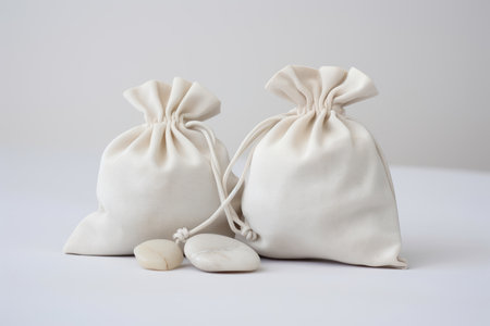 White silk cloth bags with laces for jewelry stand on a table with stonesの素材