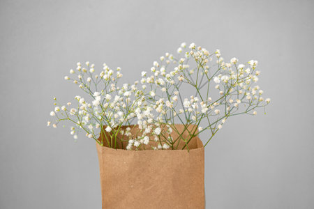 Craft packaging with small white gypsophila flowers on a gray background. View from above. Copy space with space for textの写真素材