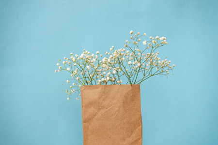 Craft package with gypsophila flowers on a bright blue background. view from above. Copy space with...