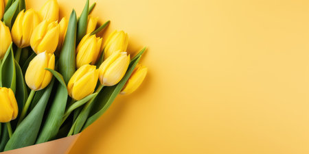 Fresh tulips in a craft envelope on a yellow background, gift conceptの素材