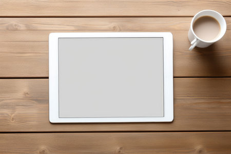 The tablet is lying on a wooden table with a cup of coffee, a place for textの素材
