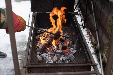 Kindling a fire in the grill, turning over burning coals for a barbecueの写真素材