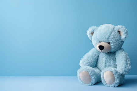 A blue teddy bear sits on a blue background, a place for textの素材