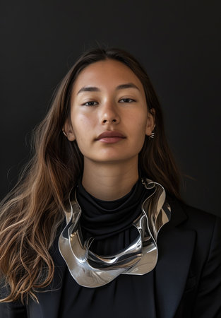 Portrait of a poised young woman wearing a bold metallic necklaceの素材
