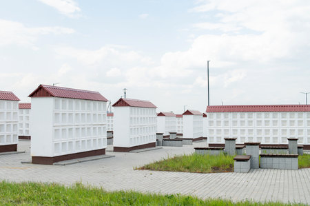 Rows of white walls for the burial of ashes after cremation. Empty cells for urns with ashes. Construction of the columbarium. Benches for resting in the cemeteryの写真素材