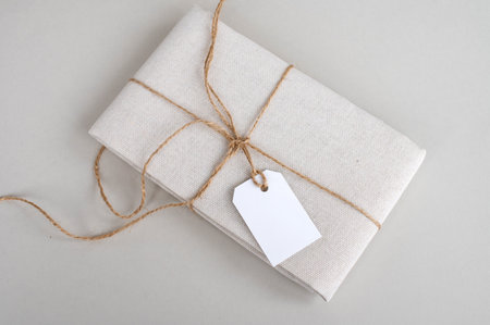Empty price tag on white fabric, label mockup, folded fabric with tag on white background