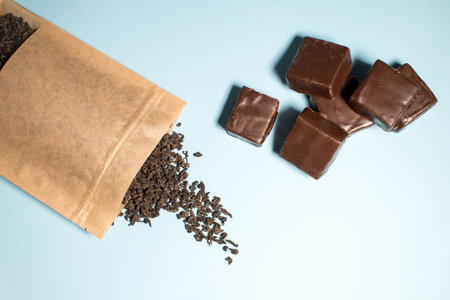 Craft paper pouch of loose tea leaves with chocolate treats on a blue background