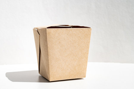 A box of craft cardboard for takeaway food. Closed container for Chinese food isolated, top view. Brown box on a white background, space for textの写真素材