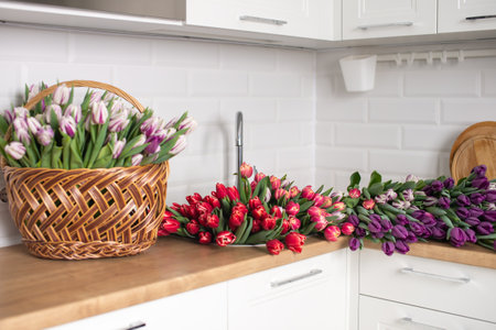A large number of tulips of different colors lies on the table in the kitchen. Flowers in the sinkの写真素材