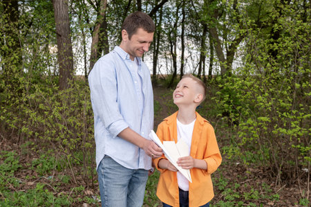 A man spends father's day in nature with a child playing with paper airplanes. Walk outdoorsの写真素材
