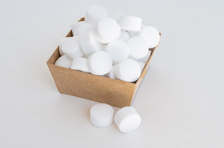 White tablets of pressed salt for the dishwasher close-up. Isolated capsules. Place for textの写真素材