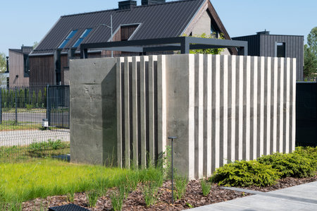 Concrete enclosing decorative wall near the lawn on the plot. Construction for garbage cansの写真素材