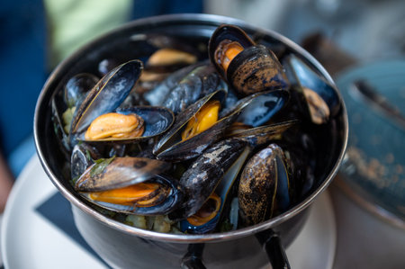 Fresh steamed mussels in a black pot, a seafood delicacyの写真素材
