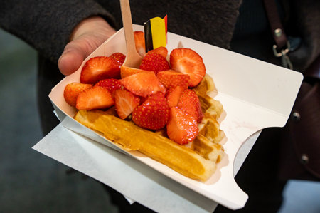 A paper tray with waffle and fresh strawberries heldの写真素材