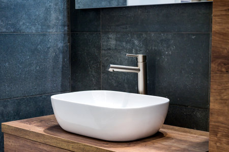 A modern basin sink with stainless steel faucet on a wooden vanityの写真素材