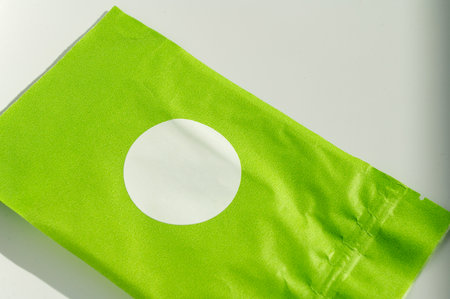 Round white sticker on green poly mailer envelope. Eco-friendly packaging and shipping concept for e-commerce with copy spaceの写真素材