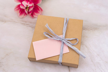 Gift box with pink note on marble background. Flat lay composition with copy space. Celebration and gift-giving concept for design and printの写真素材
