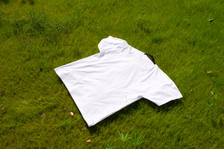 A mockup of a white T-shirt with a short sleeve lies on the lawnの写真素材