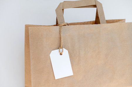 White tag on kraft bag handles, label on recycled paper bag.の写真素材