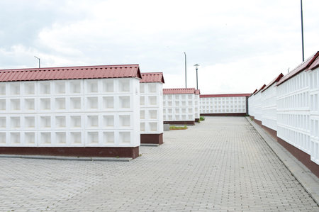 Rows of white walls for the burial of ashes after cremation. Empty cells for urns with ashes. Benches for relaxation near the columbariumの写真素材