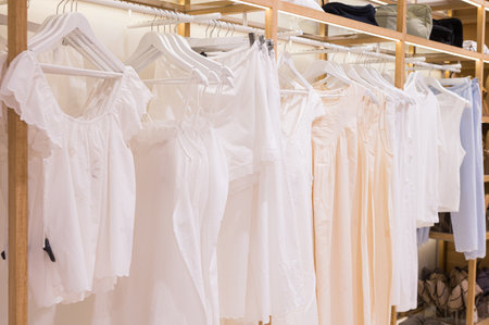 Variety of white casual dresses hanging on wooden rack in storeの写真素材