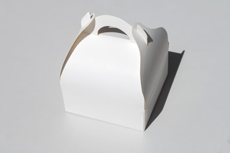 White cardboard box for a takeaway cake, highlighted on a white background with a clipping outline with a carrying handleの写真素材